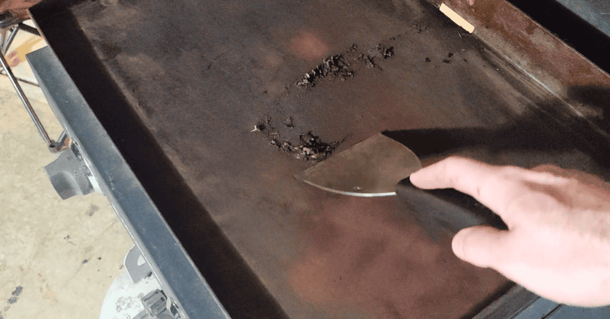 scraping the rust off a blackstone griddle with a scrapper