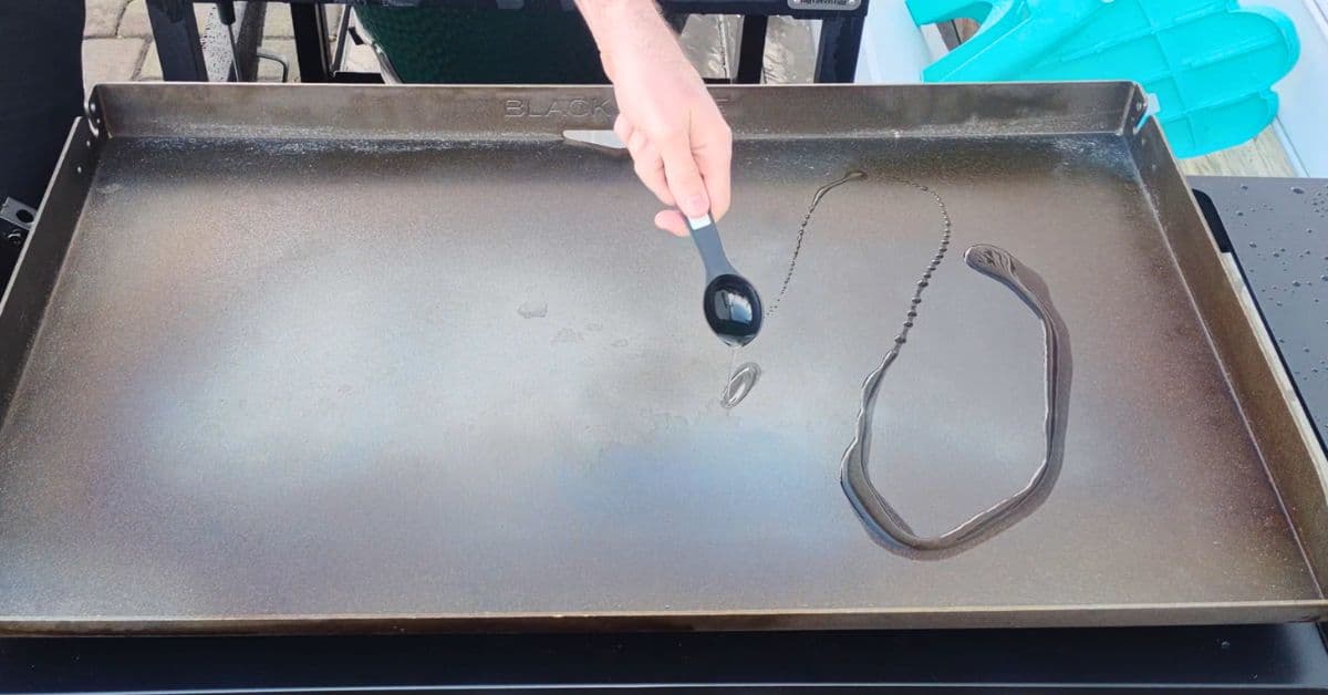 oil being poured onto a blackstone griddle for seasoning.