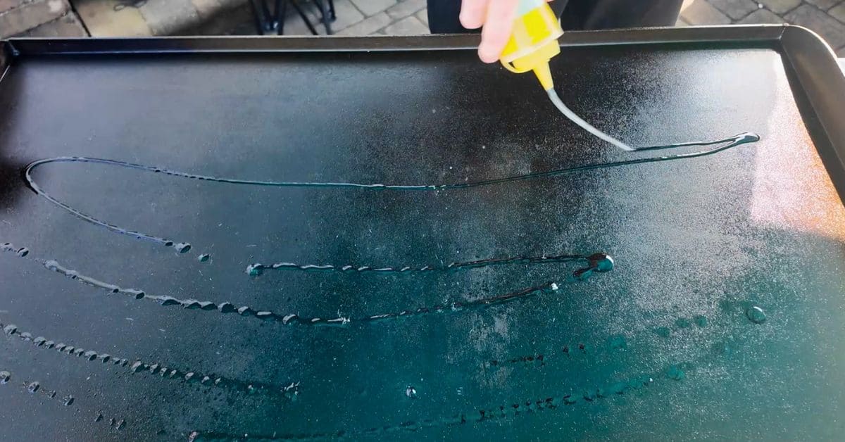 Oil from a squirt bottle going down on a well seasoned blackstone griddle.