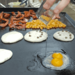 Pancakes, bacon, eggs and potatoes on a blackstone griddle.