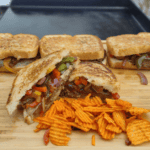 sausage, peppers, and onions on toasted bread on the griddle
