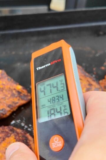 a thermometer and chicken on a Blackstone griddle