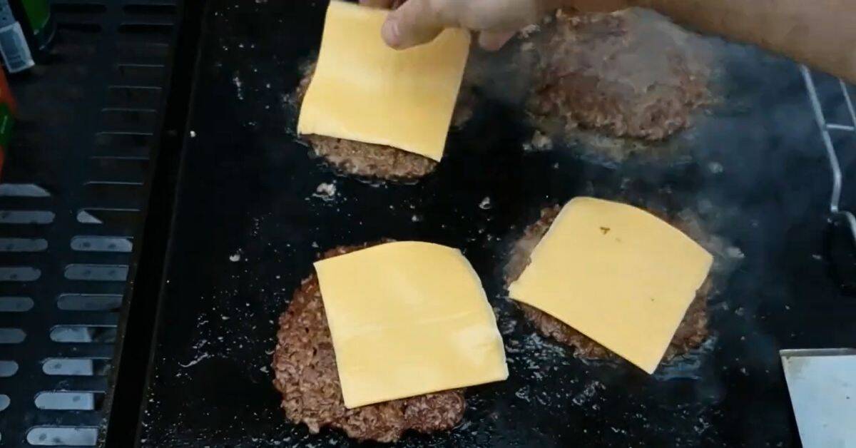 Cheese slices added to the tops of the burgers.