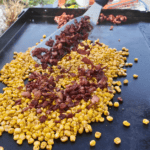 Chopped Bacon and Corn on a blackstone griddle for bacon fried corn.