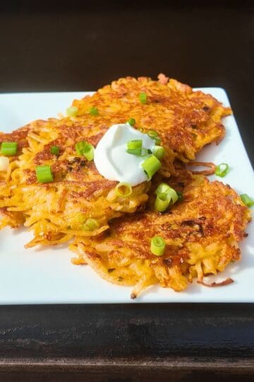 shredded hash browns on a white plate on a blackstone griddle