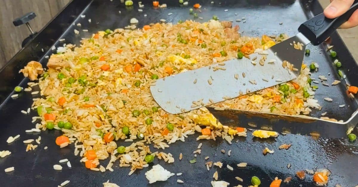 chicken fried rice on a blackstone griddle.  Two spatulas spreading it out