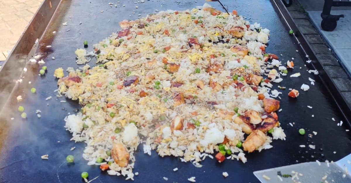 chicken fried rice with a cup of soy sauce being poured on it.