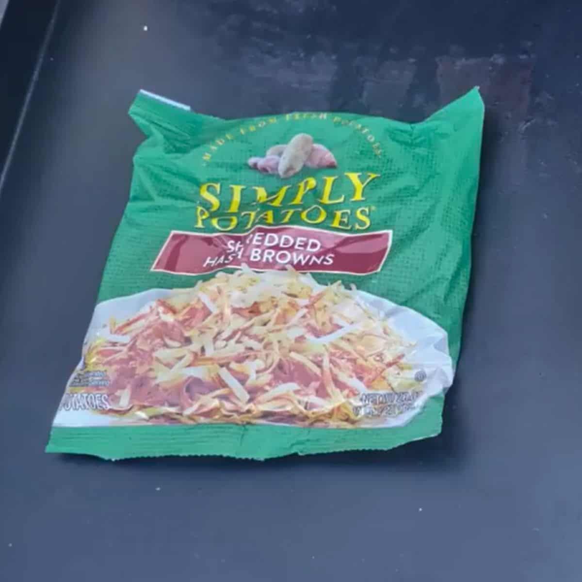 A green bag of simply potato fresh shredded hash browns on a griddle