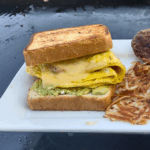 A hearty sandwich of egg cheese, bacon and avocado on griddled texas toast