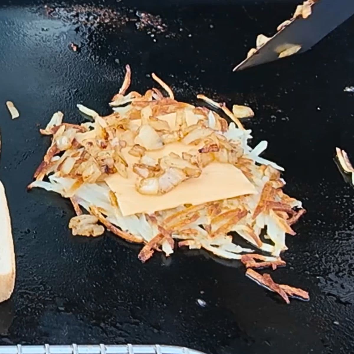 Crispy golden hash browns with american cheese and griddled onions on top.  all on a blackstone griddle