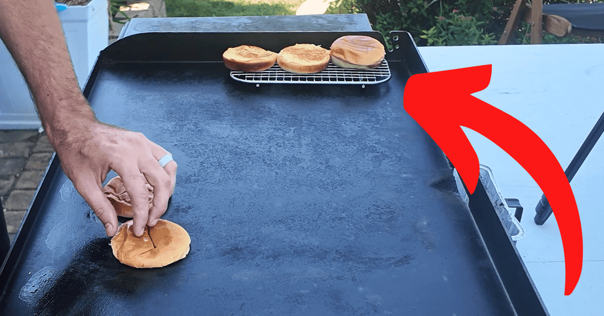 I blackstone griddle with a small wire rack holding toasted hamburger buns