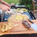 Hibachi chicken, steak, fried rice, and vegetables cooking on a Blackstone griddle.