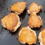 Cripsy golden brown chicken thighs on a Blackstone griddle