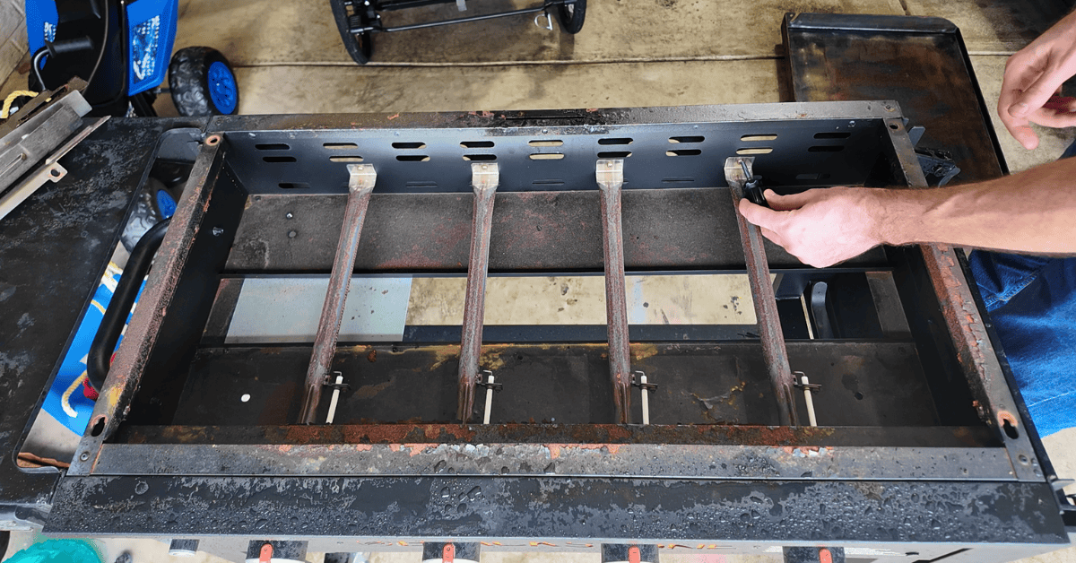 a screw driver removing the burner froma blackstone griddle